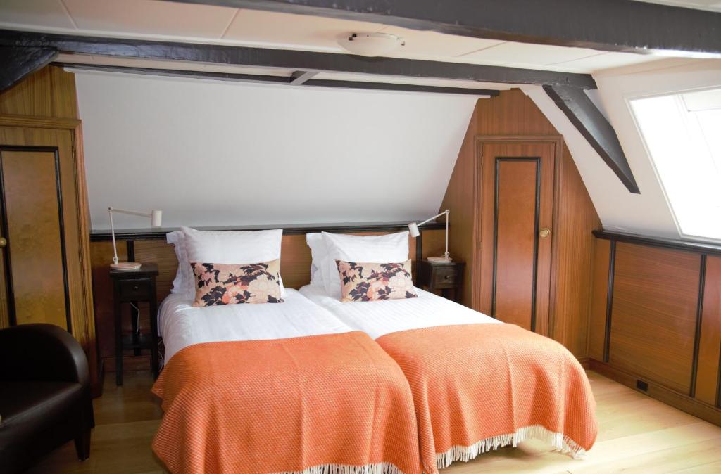 een slaapkamer met een bed met een oranje deken bij Logement Garjen in Harlingen