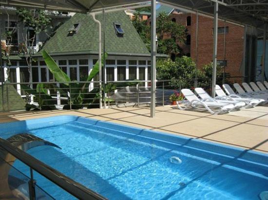 a swimming pool with chairs and a house at Ivan Da Mariya Guest House in Lazarevskoye