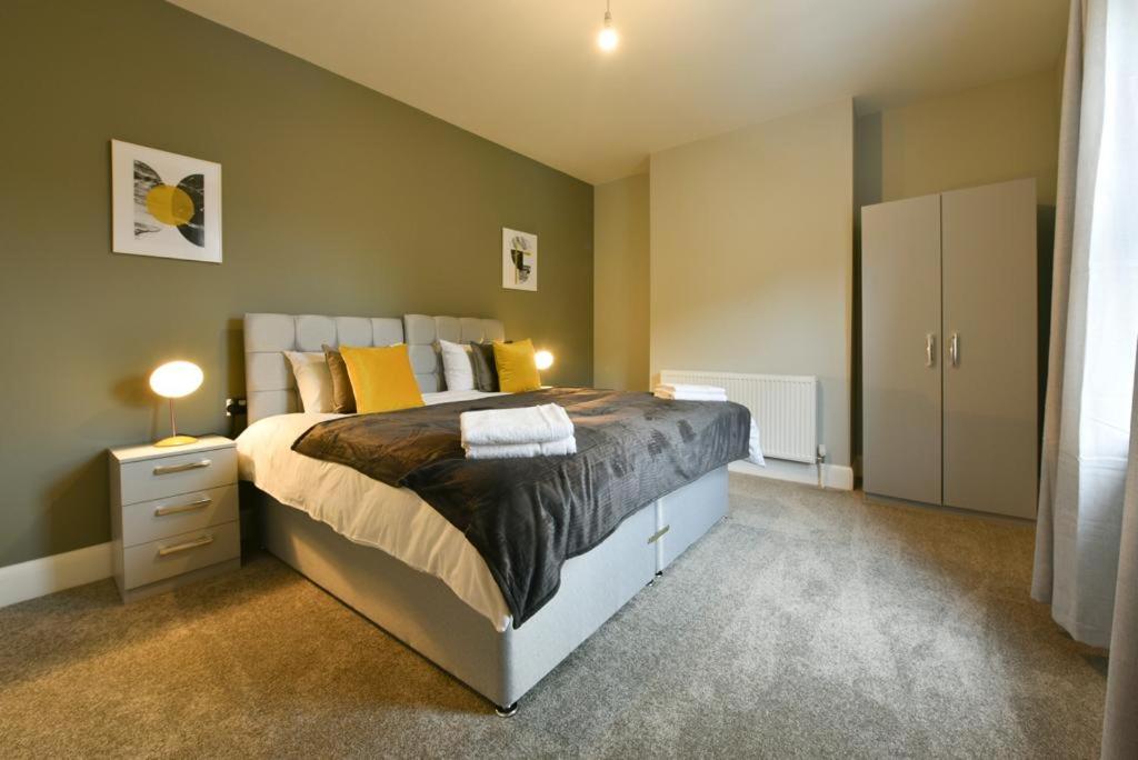 a bedroom with a large bed with yellow pillows at 3-Bedroom Luxury Home in Horbury