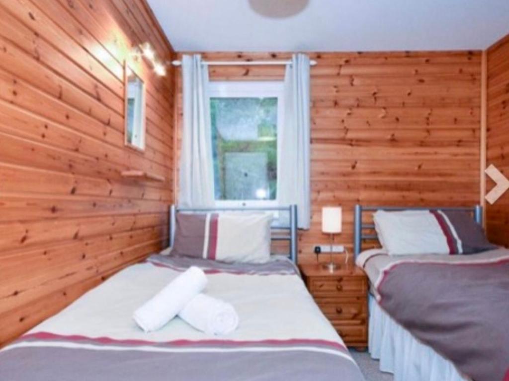 a bedroom with two beds and a window at Ben Rinnes Lodge Glenlivet Highlands in Auchnastank