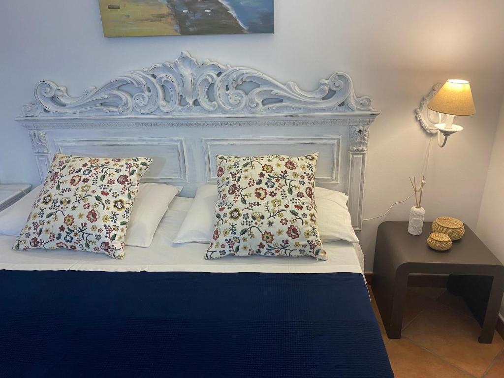 a bed with a white headboard with pillows and a table at Tyrrhenian Sea Apartment in Torre Faro