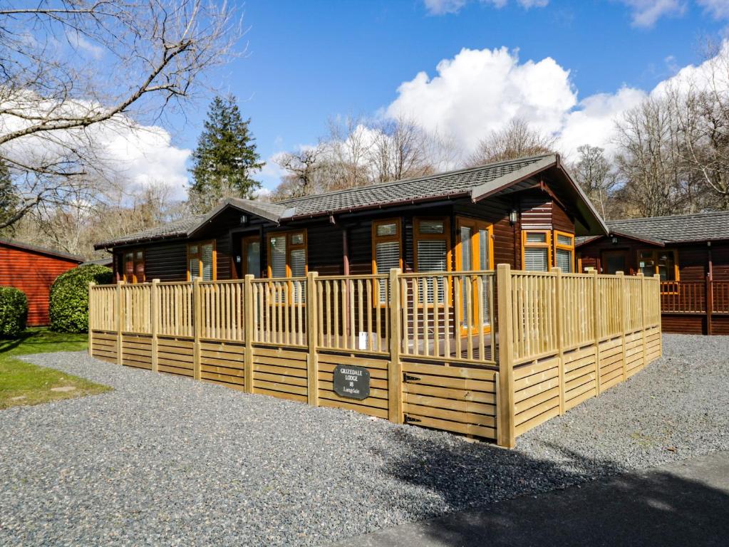 una cabaña de madera con una valla delante en Grizedale Lodge en Windermere