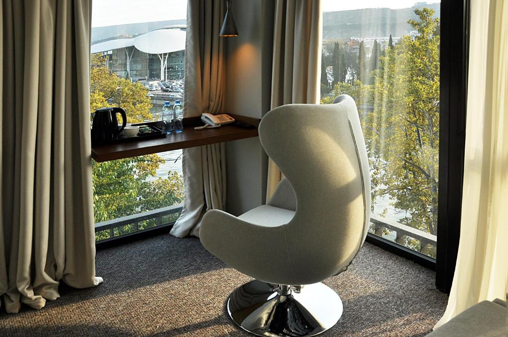 a white chair sitting in front of a window at River View Hotel Tbilisi in Tbilisi City
