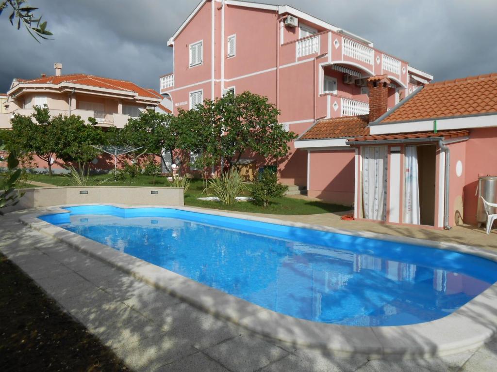 una piscina azul frente a una casa rosa en Villa Apolonija, en Zadar