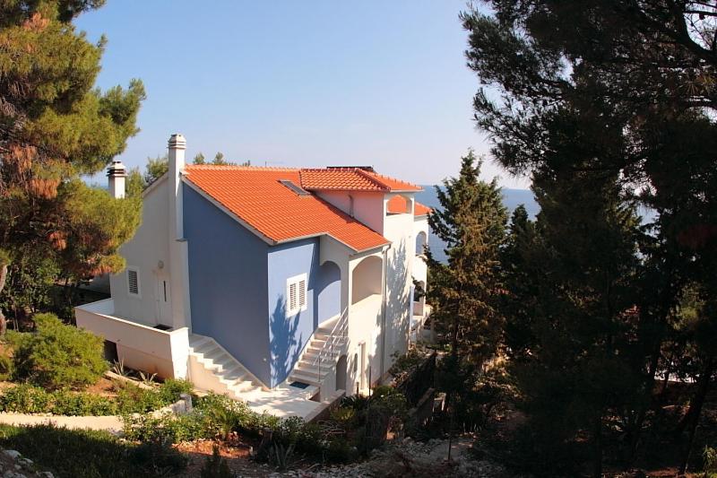 a white house with an orange roof on a hill at Apartments Maja in Hvar