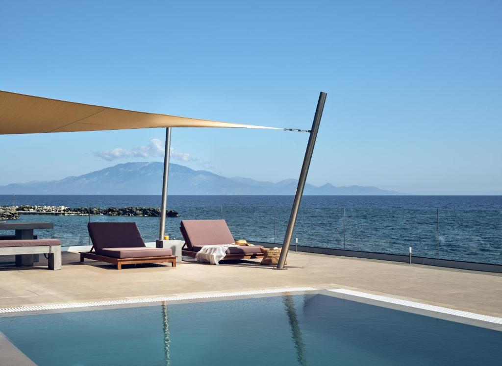 una piscina con 2 sillas y vistas al océano en LaMer SeaFront Villa, Zante Zen By ThinkVilla en Kipseli