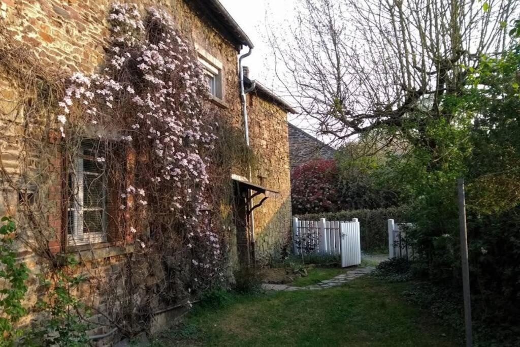 uma velha casa de tijolos com flores a crescer nela em Gîte La Lisière, en Brocéliande em Néant-sur-Yvel