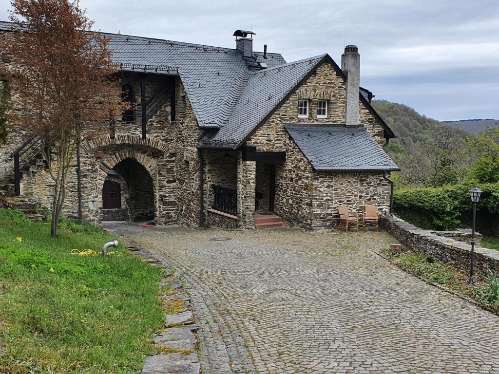 una antigua casa de piedra con una entrada de adoquines en Wächterhaus auf der Sauerburg, en Sauerthal