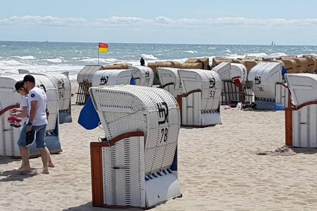 a person walking on a beach with stacks of chairs at Ferienwohnung Berolina 116 in Dahme