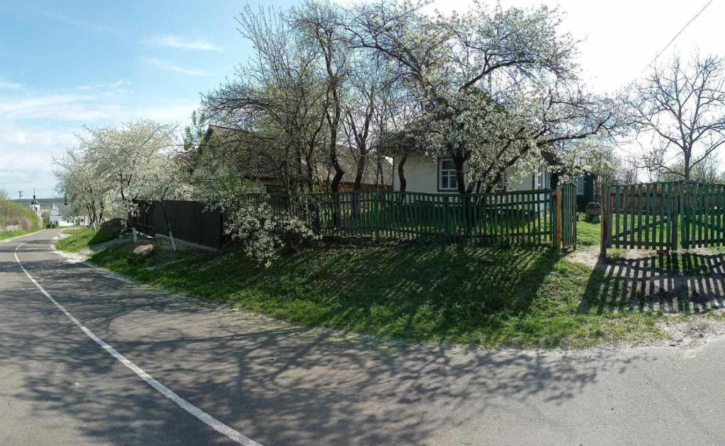 una valla frente a una casa con árboles en Медова садиба en Subbotov