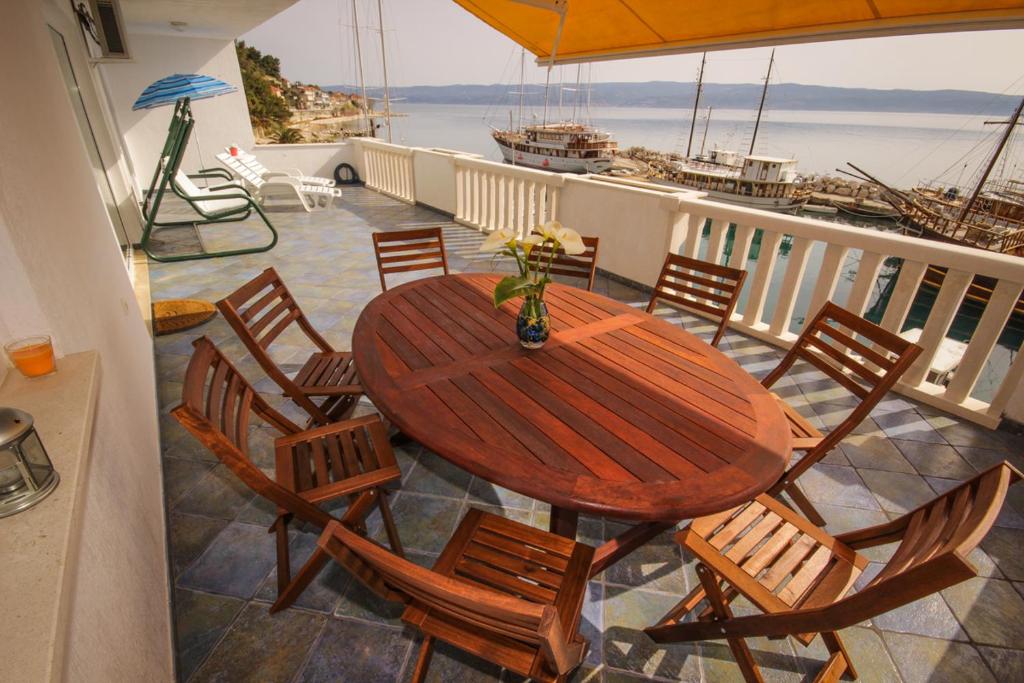un tavolo in legno con sedie su un balcone con barca di Apartmani Kristijan a Jesenice