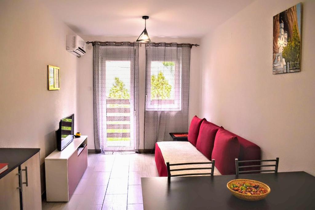 a living room with a red couch and a table at Apartman Ljutovac in Gornja Toplica