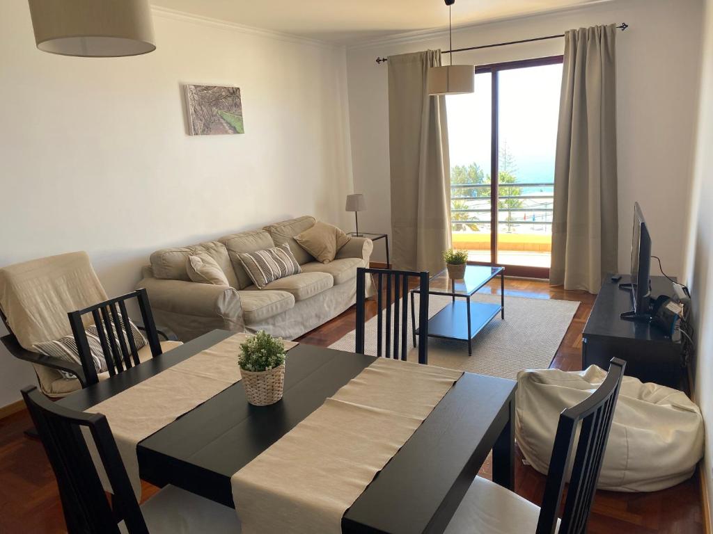 uma sala de estar com uma mesa e um sofá em FLH Garajau Balcony with Pool no Caniço