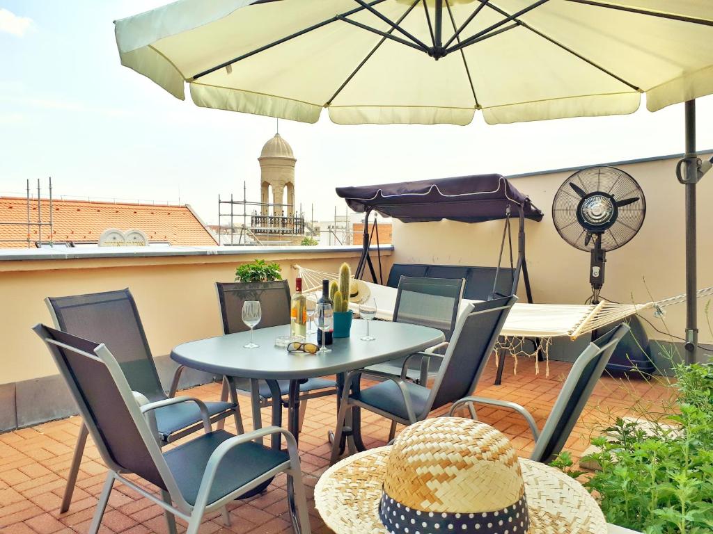 een patio met een tafel en stoelen en een parasol bij Rumbach Terrace Apartment in Boedapest