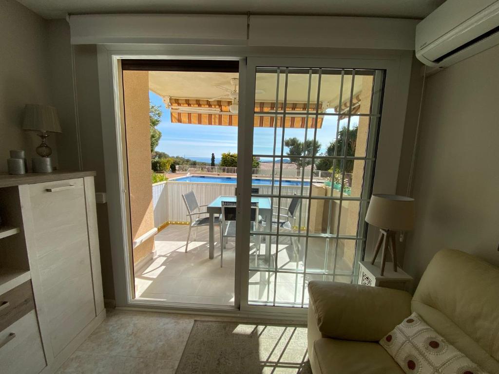 Una sala de estar con una puerta corrediza de vidrio con vista a una piscina. en Karin Palma Fiesta-Vallpineda-Sitges, en Sant Pere de Ribes