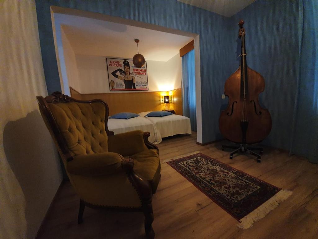 Zimmer mit Gitarre, Stuhl und Bett in der Unterkunft Cuore Alpino in Olivone