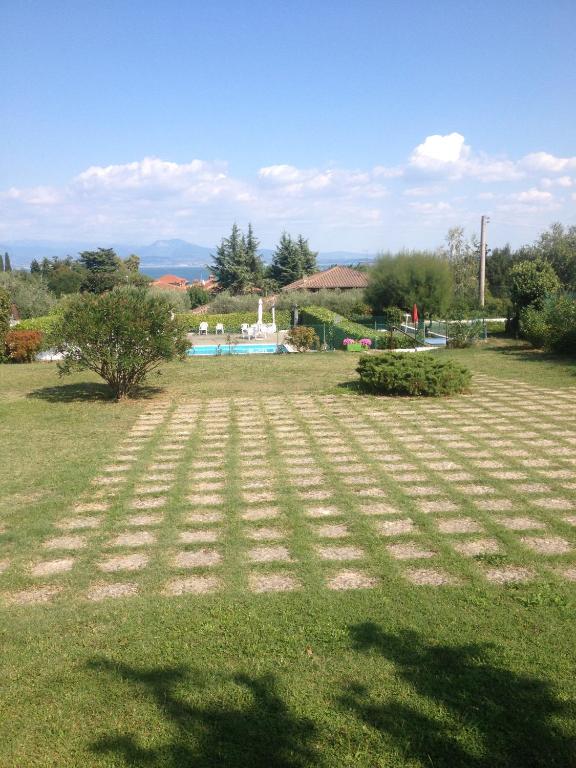a large field of grass with a pool in the background at Residenza Il Porto in Padenghe sul Garda