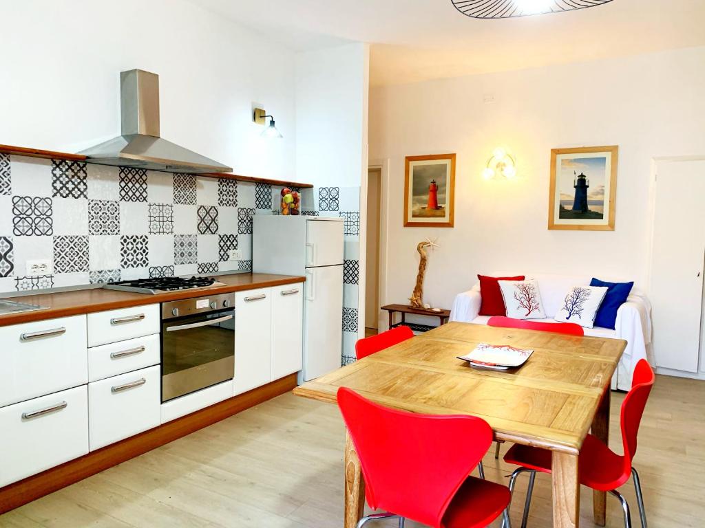 a kitchen and dining room with a wooden table and red chairs at Appartamenti Tina Paolini 1 piano terra con parcheggio in Castiglione della Pescaia
