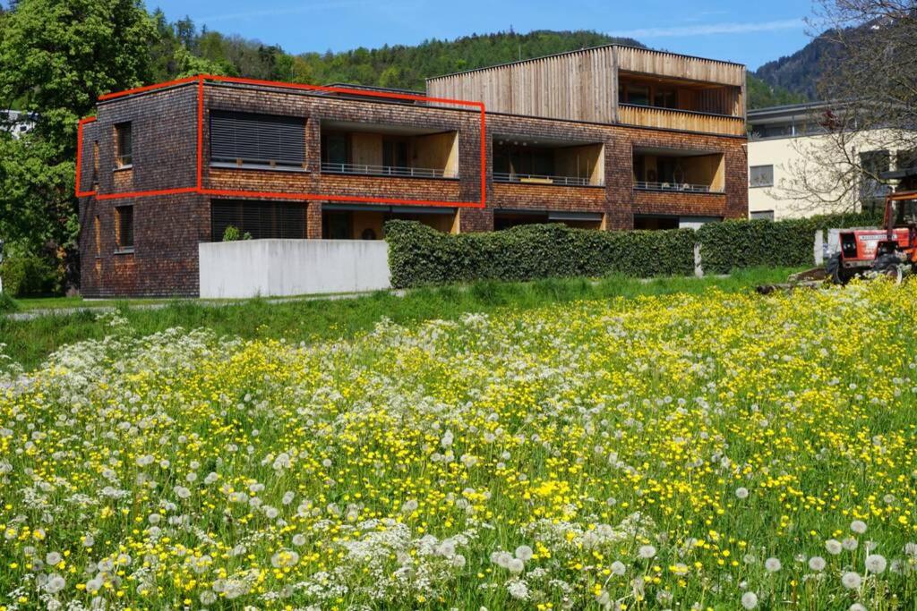 a building in front of a field of flowers at Terrassenwohnung in prämierter Wohnanlage in Klaus