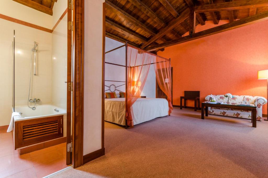 a bedroom with a bed and a tub and a sink at Palacio San Facundo in Segovia