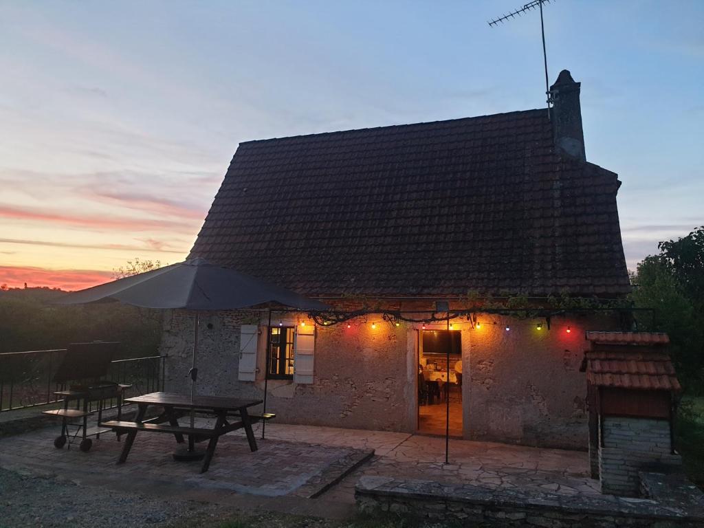 a house with a picnic table and an umbrella at Cœur de Causse in Blars