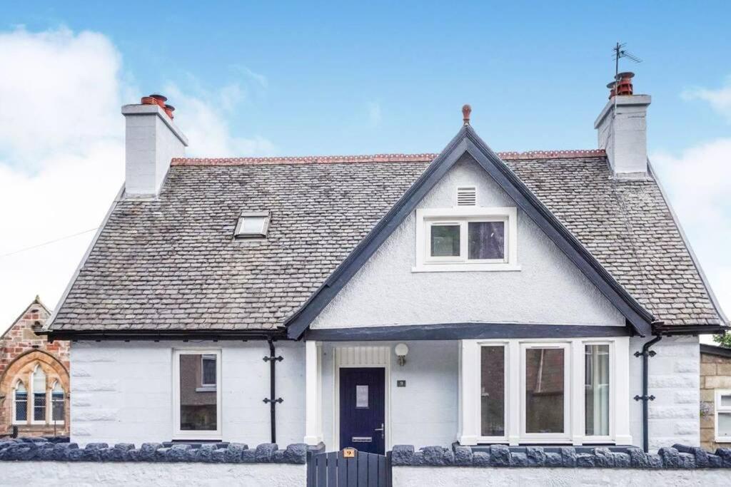 une maison blanche avec un toit noir dans l'établissement Seacot Cottage in the heart of the Highlands, à South Kessock