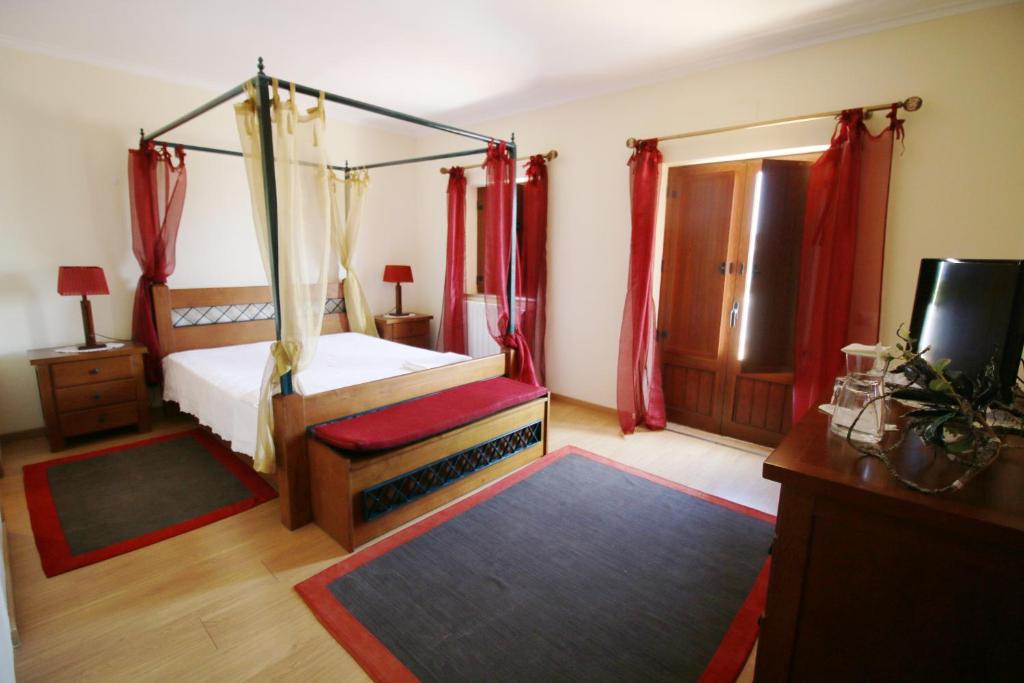 a bedroom with a canopy bed and a television at Paz e Natureza in São Brás de Alportel