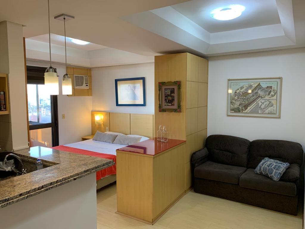 Zimmer mit einem Bett und einem Sofa sowie einer Küche in der Unterkunft Apartamento Beverly Hills Studio in Porto Alegre
