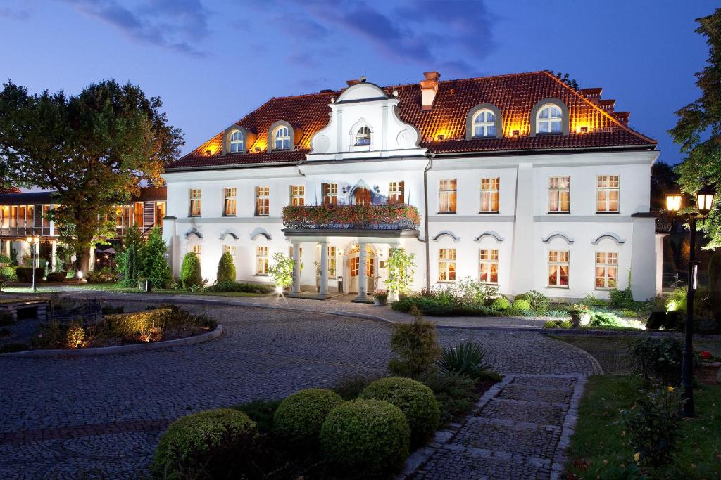 ein großes weißes Gebäude mit rotem Dach in der Unterkunft Pałac Czarny Las (50 km od Katowic) in Wożniki