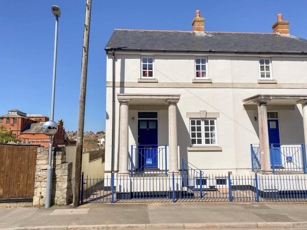 una casa blanca con una valla azul en Ashwood, en Weymouth