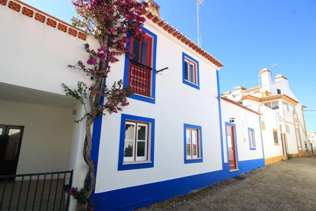 a white and blue building with flowers on it at Casa Alentejana in Vila Nova de Milfontes