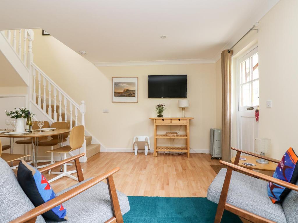 a living room with a table and a tv at Pugwash Cottage in Falmouth