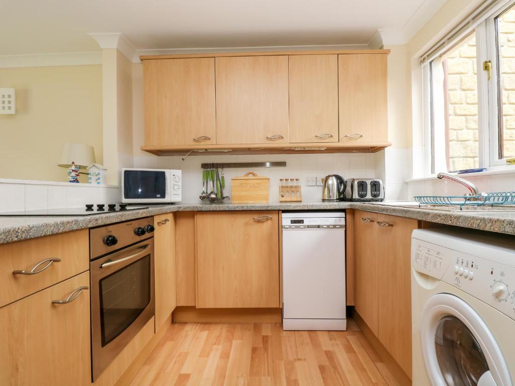 a kitchen with wooden cabinets and a white dishwasher at Pugwash Cottage in Falmouth