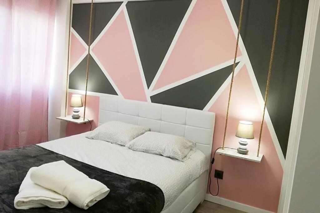sypialnia z łóżkiem z różowymi i szarymi ścianami w obiekcie Ria Center Apartment - Left w Faro
