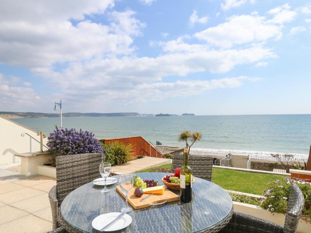 uma mesa com uma taça de fruta em cima de uma varanda com praia em Ocean Wave em Weymouth