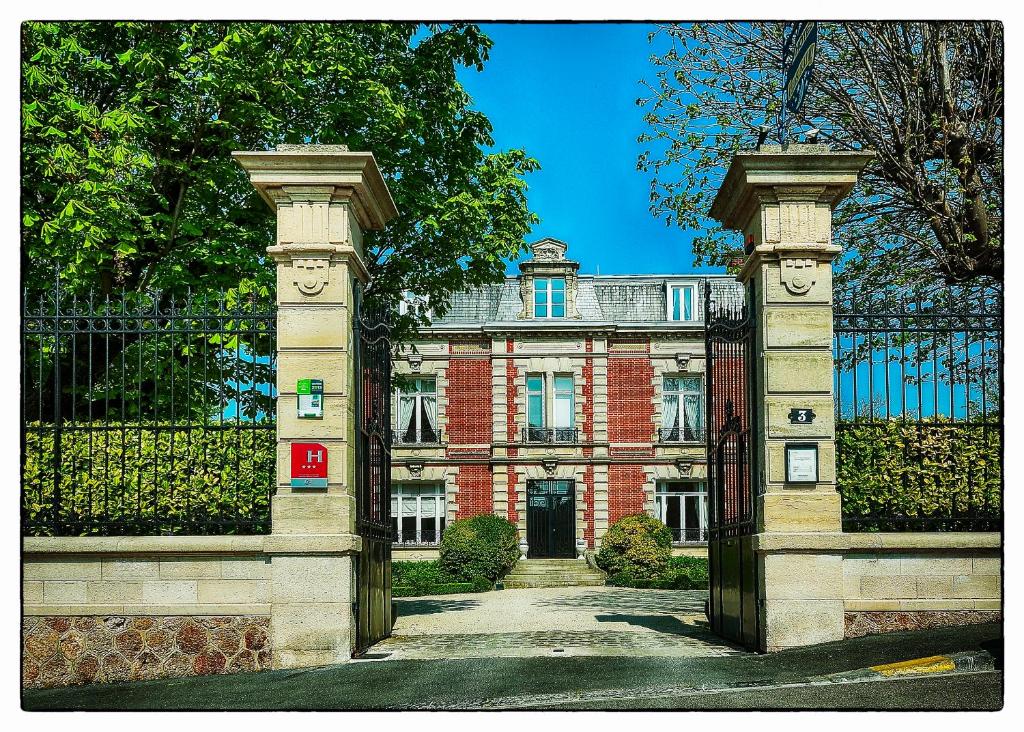 uma entrada para um edifício de tijolos vermelhos com um portão em Hotel Le Clos Raymi em Épernay