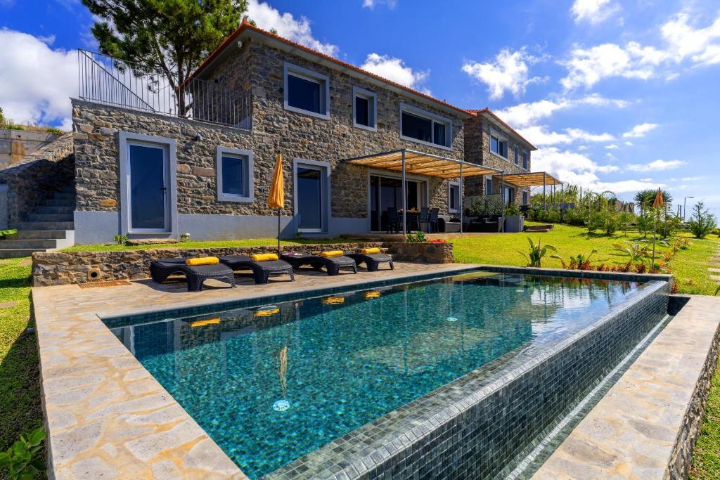 a swimming pool in front of a house at Villa Flora - Nature & Tranquility - Heated pool optional in Jardim do Mar