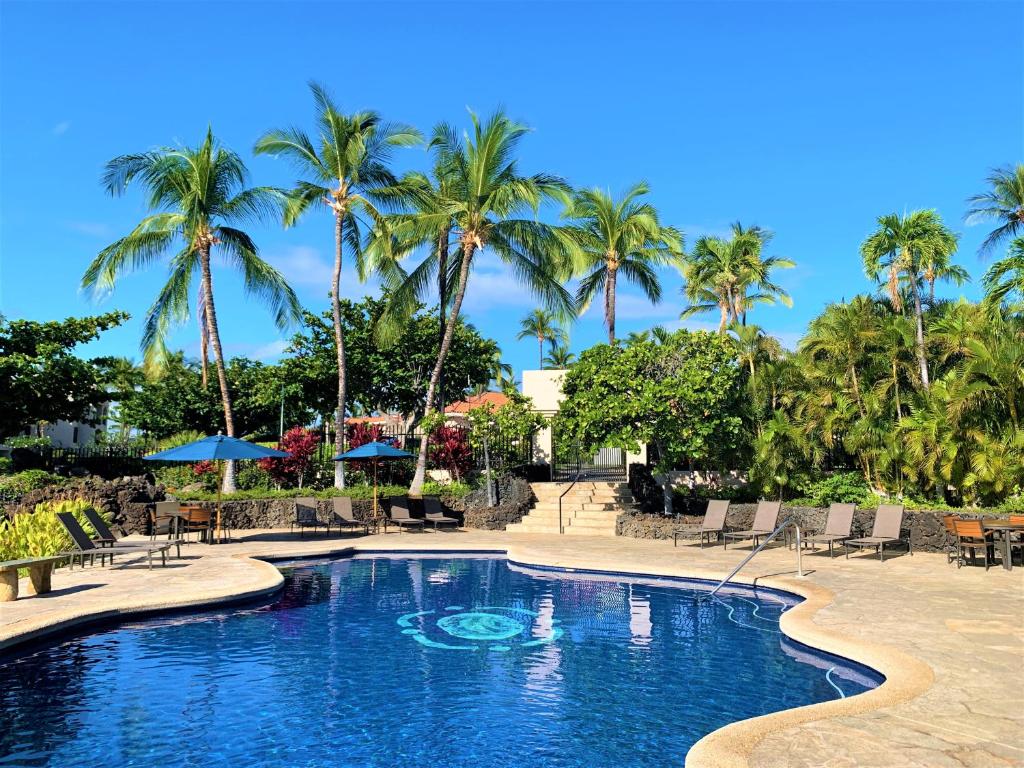 uma piscina num resort com palmeiras em Coconut at Shores - Waikoloa Beach Resort em Waikoloa