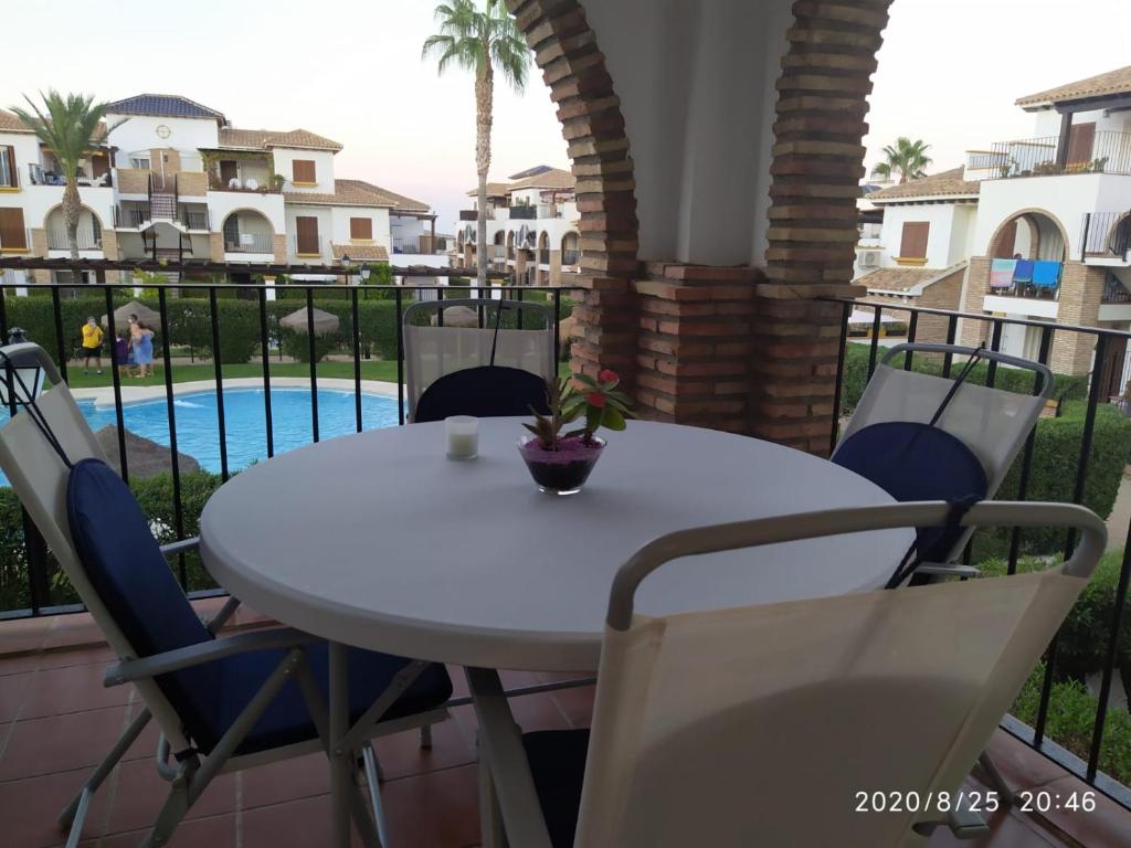 d'une table et de chaises blanches sur un balcon avec piscine. dans l'établissement APARTAMENTO Al Andalus Residencial, à Vera