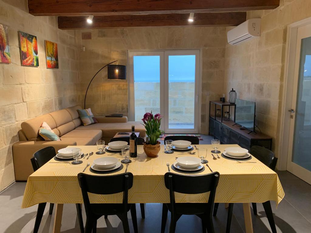 una sala da pranzo con tavolo e sedie gialli di Tac-Cnic Heritage Living - Apartment, Spa Suite & Spectacular Views a Żebbuġ