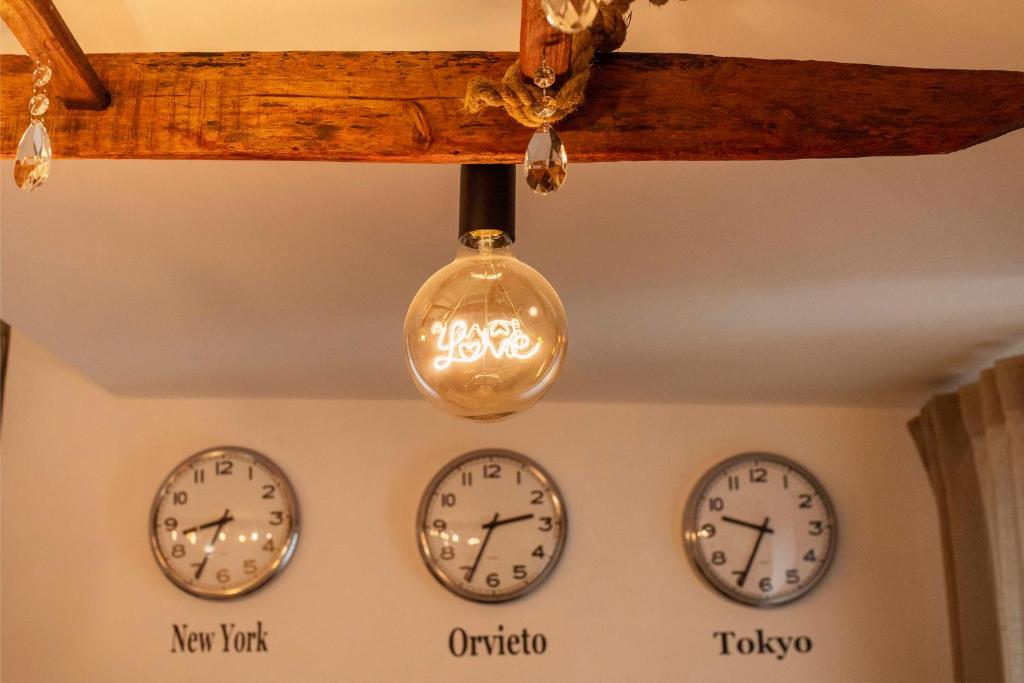 three clocks on the wall next to a light fixture at Nel cuore di Orvieto in Orvieto