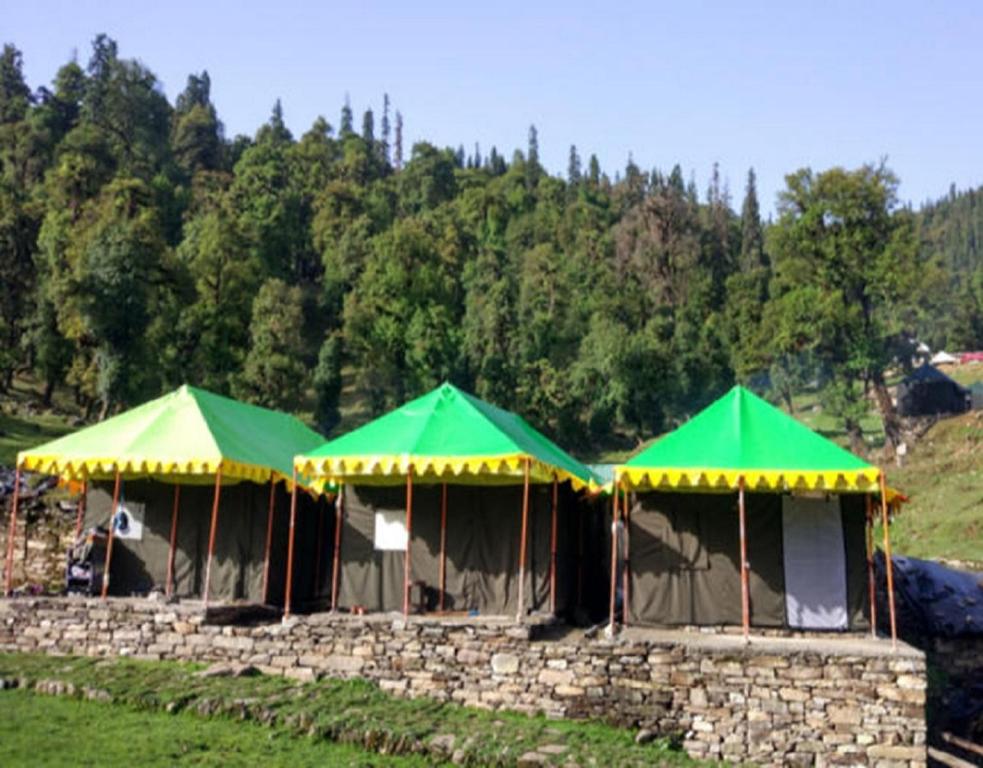two green and yellow umbrellas on a stone wall at Camping Huts at Lord Shiva Camps in Sari