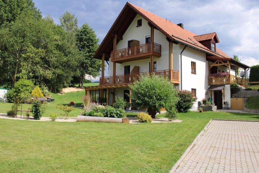 une maison avec une cour verdoyante devant elle dans l'établissement Gästehaus Sporrer, à Neualbenreuth