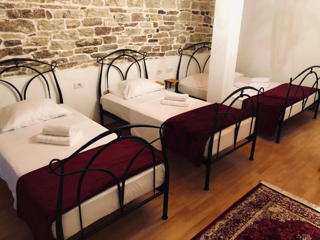 3 camas en una habitación con una pared de ladrillo en Stone House Obelisk, en Gjirokastra