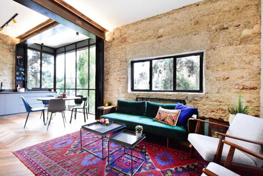 a living room with a green couch and a brick wall at Jerusalem of concrete&stell in Jerusalem