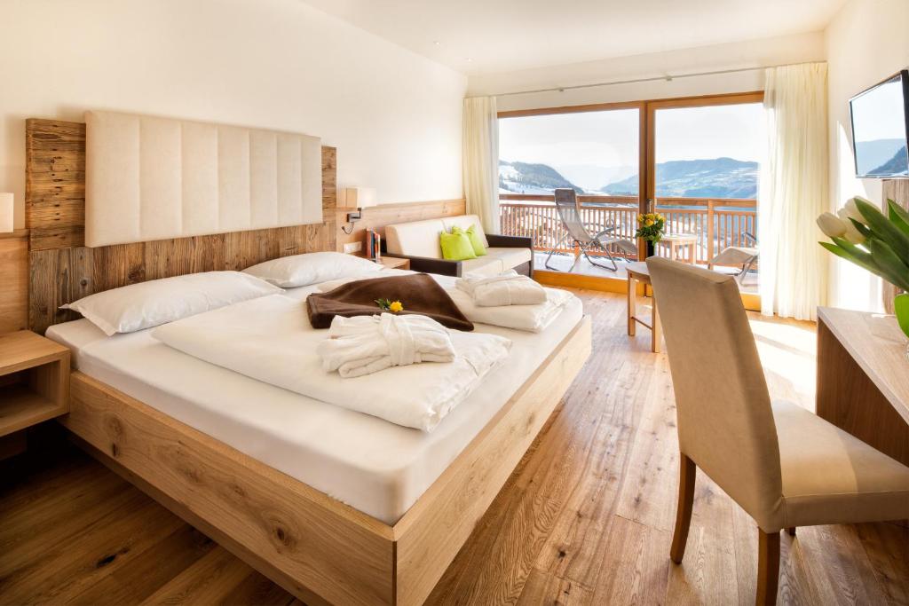 a bedroom with a large bed and a balcony at Hotel Gasthof Kircher in Völs am Schlern