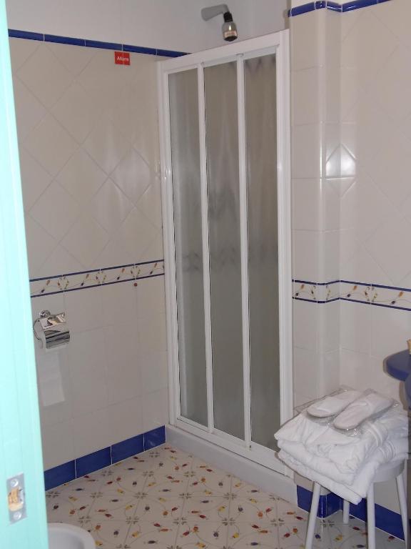 a bathroom with a sliding glass door with towels on a stool at Hotel Le Terrazze in Conca dei Marini