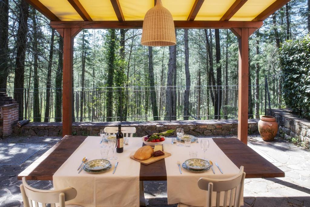 einen Esstisch mit Stühlen auf einer Terrasse mit Bäumen in der Unterkunft Podere Mocai - Cottage nel bosco in Montieri