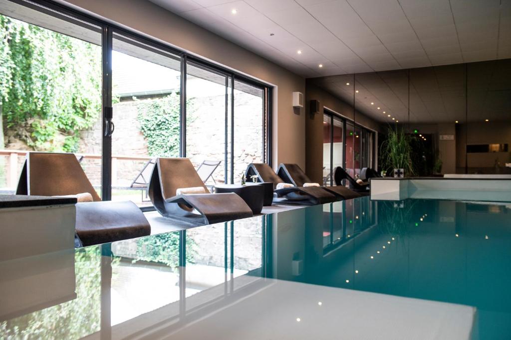 a lobby with a swimming pool with leather chairs at Relais et Châteaux Le Chambard in Kaysersberg