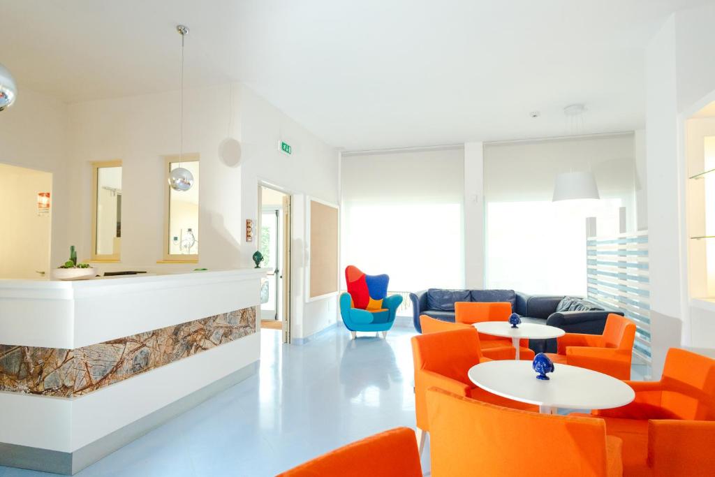 a living room with orange chairs and tables at Kalos Hotel in Maruggio